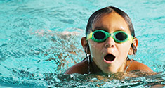 Enfant nageant dans une piscine et portant des lunettes de piscine