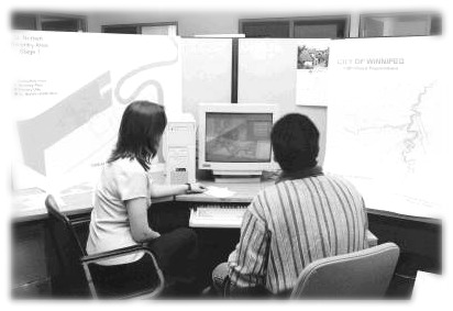 A picture of 2 employees examining maps and a computer screen image, City of Winnipeg Photo