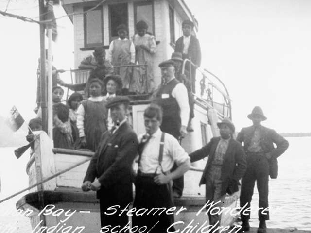 This image shows children on boats going to the Cecilia Jeffrey Indian Residential School near Shoal Lake.