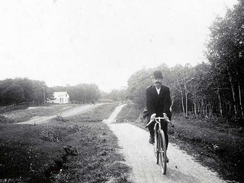 Credit: Archives of Manitoba, Item: N4549. Cyclist on Portage Avenue at Silver Heights with Sturgeon Creek in the background, circa 1900.