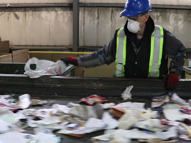 Employees have to remove plastic bags by hand at the recycling sorting facility.