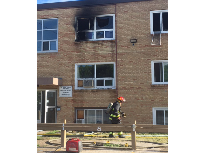 firefighter walking in front of an apartment building with fire damage