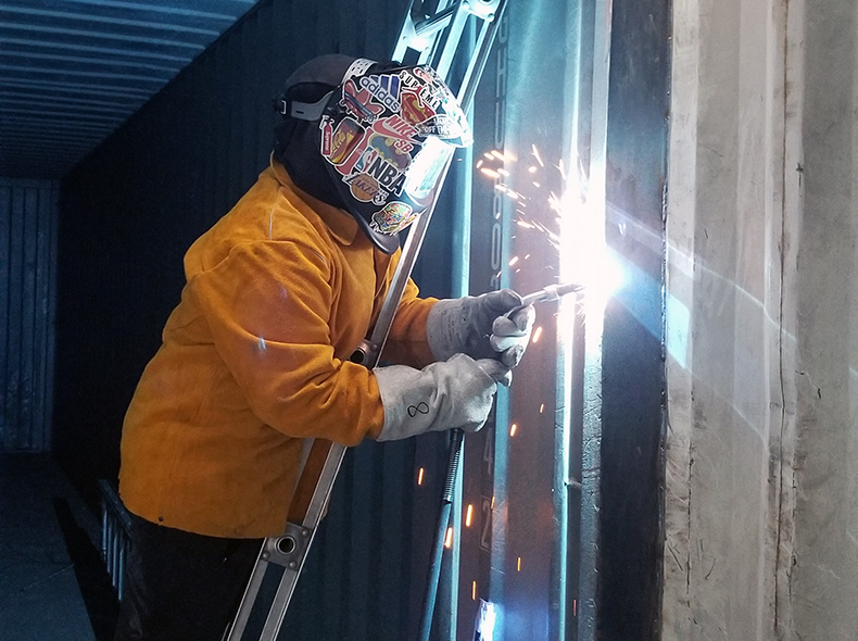 student standing on a ladder welding