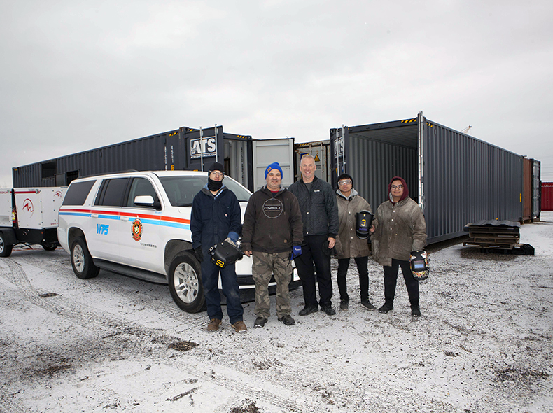 Students and instructor standing in front of shipping containers