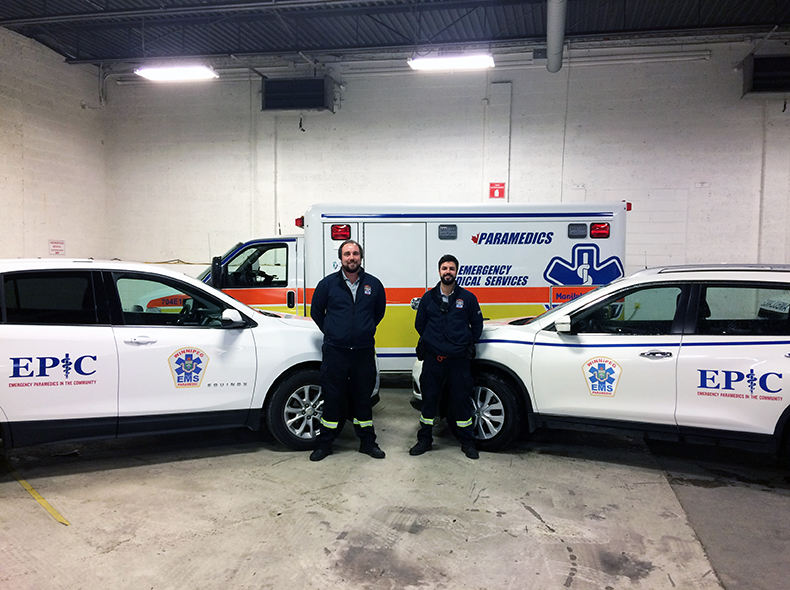 Two paramedics standing next to an ambulance