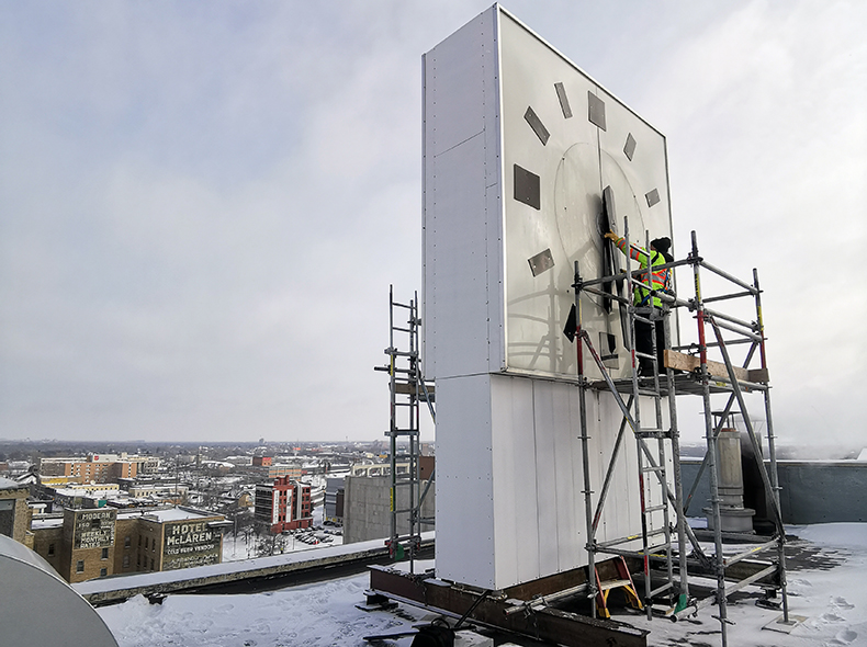 Employee adjusting the clock on the roof of 510 Main Street