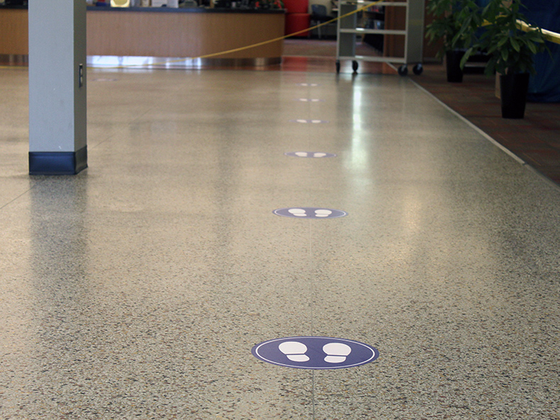 Floor decals indicate where visitors should stand while visiting a Winnipeg Public Library branch.
