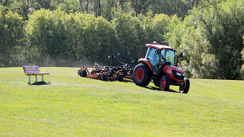 Tractor mowing grass in a park.