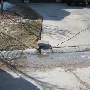 Photo of improper sump pump hose placement - Hose draining onto street