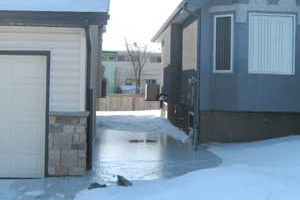 Photo of improper sump pump hose placement - Ice buildup between houses